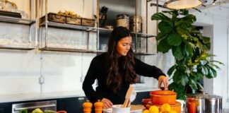 Seasonal Eating: How to Choose Healthy Ingredients Based on the Season woman standing in front of fruits holding pot's lid