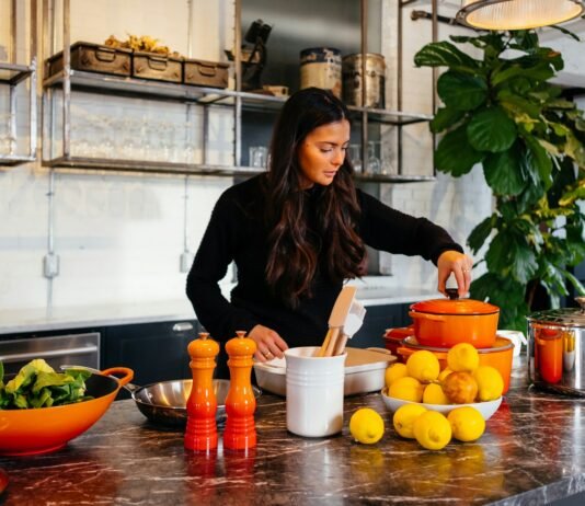 Seasonal Eating: How to Choose Healthy Ingredients Based on the Season woman standing in front of fruits holding pot's lid