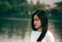 Living in Stillness: A Practical Guide to Weaving Meditation into Everyday Life woman meditating on wooden dock during daytime