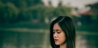 Living in Stillness: A Practical Guide to Weaving Meditation into Everyday Life woman meditating on wooden dock during daytime