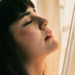 Silent Saboteur: How Sleep Deprivation Destroys Health and What You Can Do About It woman in white shirt looking down