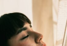 Silent Saboteur: How Sleep Deprivation Destroys Health and What You Can Do About It woman in white shirt looking down