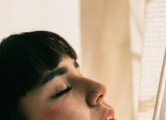 Silent Saboteur: How Sleep Deprivation Destroys Health and What You Can Do About It woman in white shirt looking down