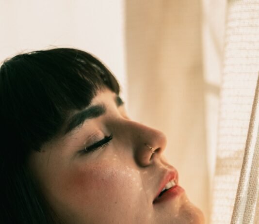 Silent Saboteur: How Sleep Deprivation Destroys Health and What You Can Do About It woman in white shirt looking down